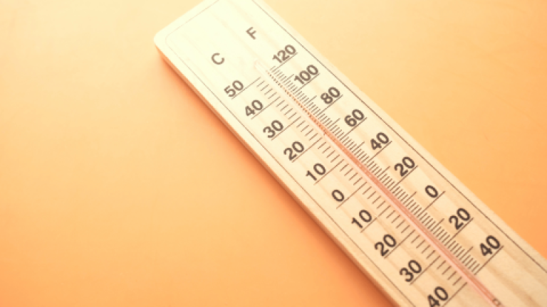 Wooden thermometer showing 30°C on an orange background